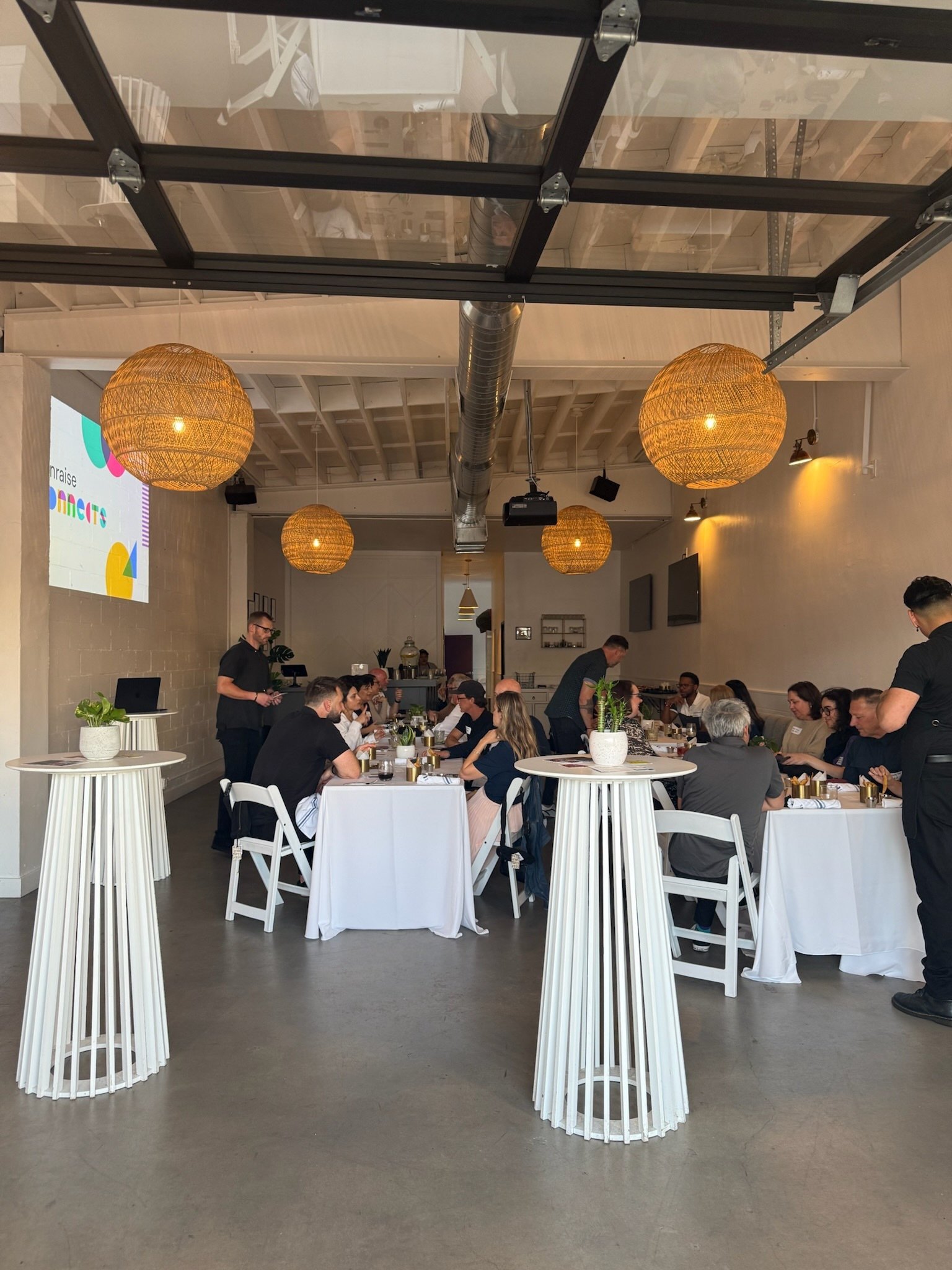 Private event venue in Costa Mesa set for an intimate dinner with candlelit tables, woven pendant lighting, and a modern indoor-outdoor space